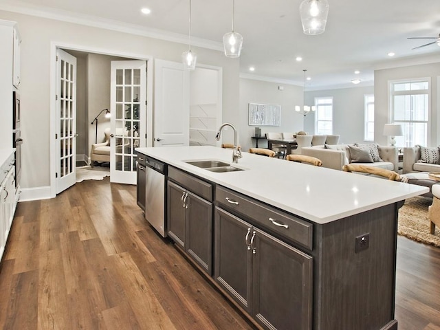 kitchen featuring dark brown cabinets, open floor plan, light countertops, a sink, and dishwasher