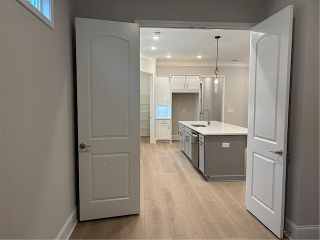 kitchen featuring crown molding, stainless steel dishwasher, light countertops, a sink, and light wood-style flooring