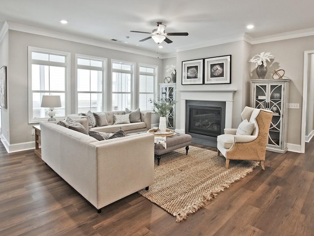 living room with baseboards, a fireplace with flush hearth, ceiling fan, and ornamental molding