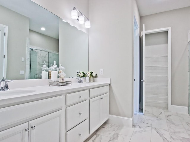 bathroom featuring double vanity, a shower stall, a sink, baseboards, and marble finish floor