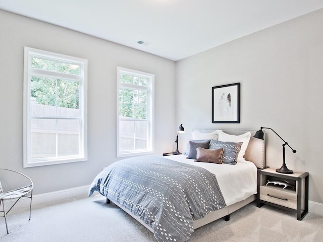 bedroom with baseboards, visible vents, and light colored carpet