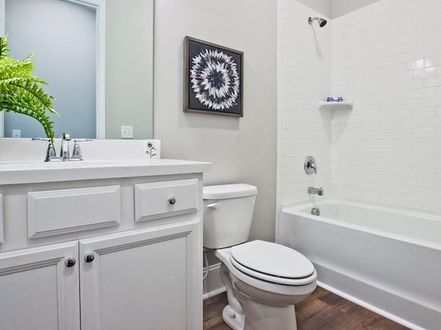 bathroom featuring vanity, toilet, wood finished floors, and shower / washtub combination