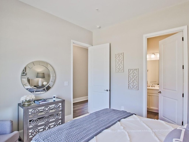bedroom featuring ensuite bathroom, a sink, and wood finished floors