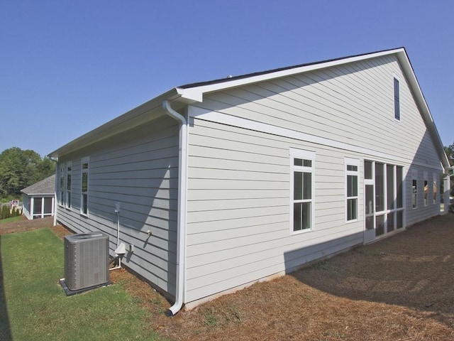 view of side of property featuring a lawn and central AC