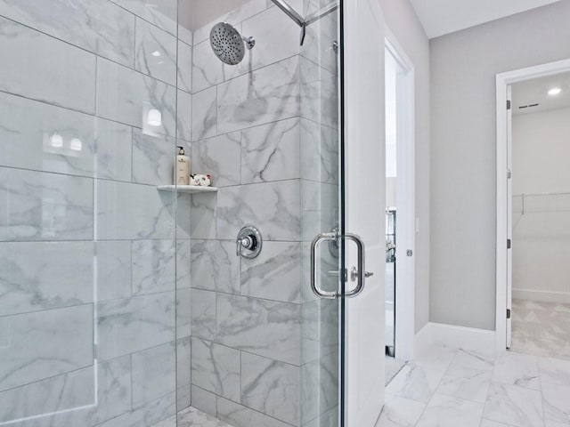 full bath with baseboards, a walk in closet, a stall shower, and marble finish floor