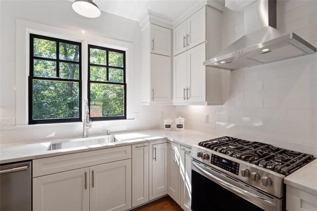 kitchen with decorative backsplash, appliances with stainless steel finishes, plenty of natural light, and wall chimney range hood