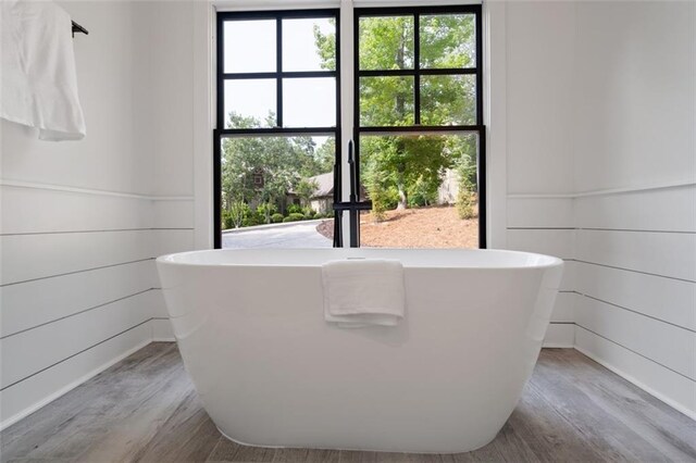 bathroom featuring hardwood / wood-style floors, a bathtub, and wood walls