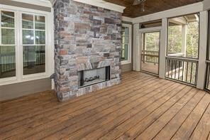 unfurnished sunroom with ceiling fan and a stone fireplace