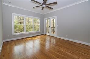 empty room featuring ceiling fan, french doors, crown molding, and dark wood-type flooring