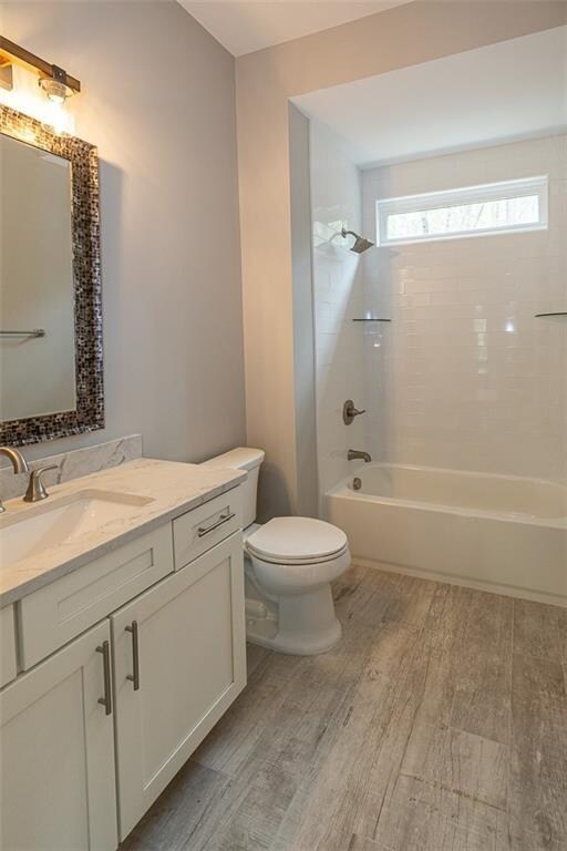 full bathroom with toilet, vanity, tiled shower / bath combo, and hardwood / wood-style flooring