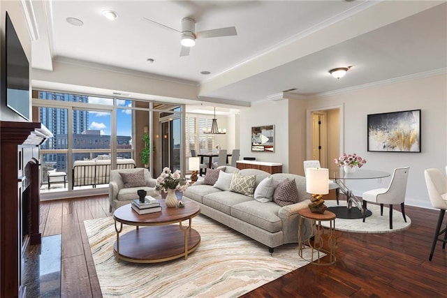 living area featuring baseboards, a fireplace, ceiling fan, ornamental molding, and wood-type flooring