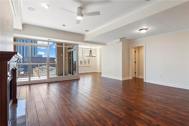 unfurnished room with ornamental molding, dark wood finished floors, a fireplace, baseboards, and ceiling fan