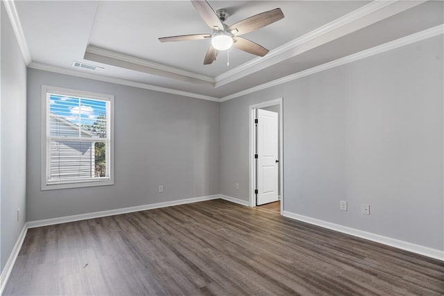spare room with a raised ceiling, baseboards, dark wood finished floors, and visible vents