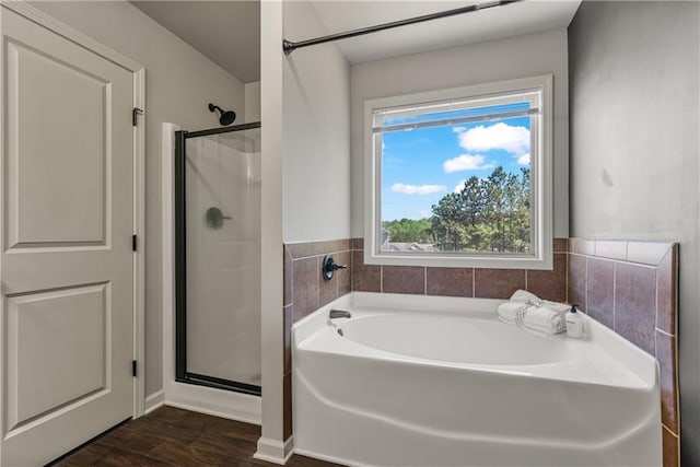 full bathroom with a shower stall, a garden tub, and wood finished floors