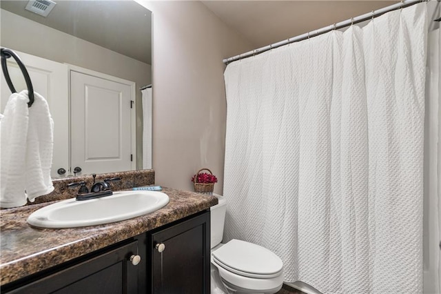 bathroom with toilet, vanity, and visible vents