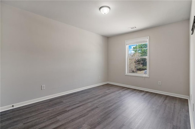 spare room featuring visible vents, dark wood-style flooring, and baseboards