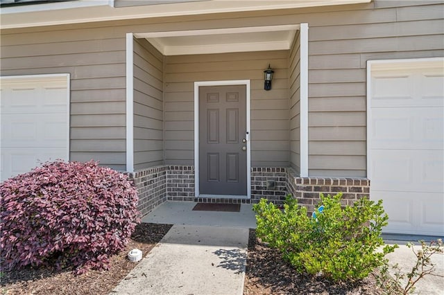 property entrance featuring a garage and brick siding