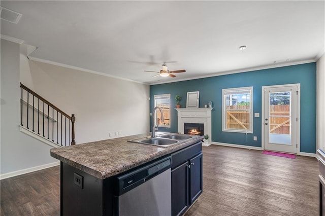 kitchen featuring dishwasher, a sink, open floor plan, a warm lit fireplace, and a ceiling fan