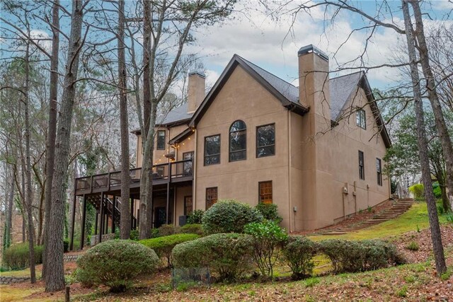 french country inspired facade with driveway, stucco siding, an attached garage, and roof with shingles