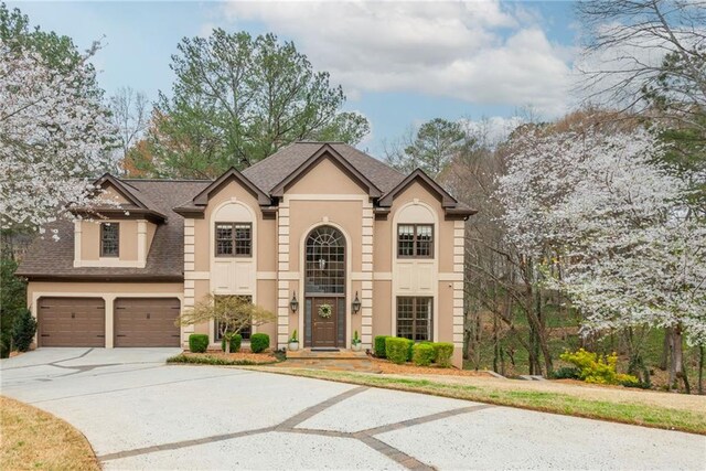 view of front facade featuring stucco siding, driveway, and a shingled roof
