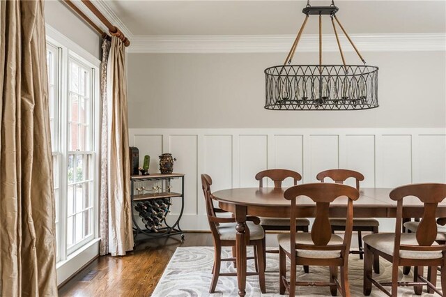 dining room featuring ornamental molding, a chandelier, wainscoting, and dark wood finished floors