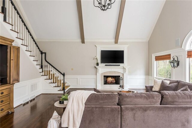 living area with stone tile floors, high vaulted ceiling, and wainscoting
