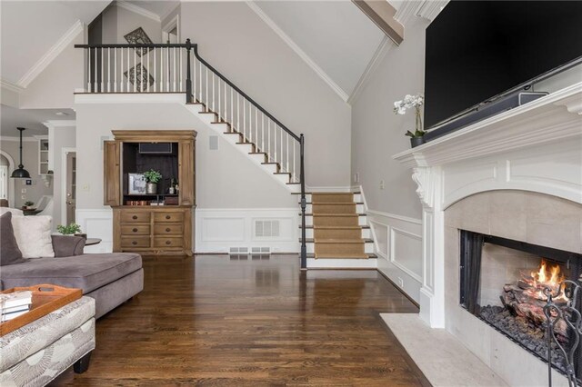 living room with decorative columns, ornamental molding, stairs, and wood finished floors