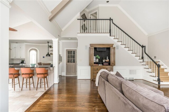 living room with high vaulted ceiling, dark wood-type flooring, beam ceiling, a warm lit fireplace, and a notable chandelier