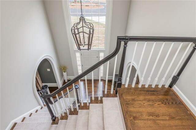 stairs featuring visible vents, a chandelier, ornamental molding, wood finished floors, and a tray ceiling