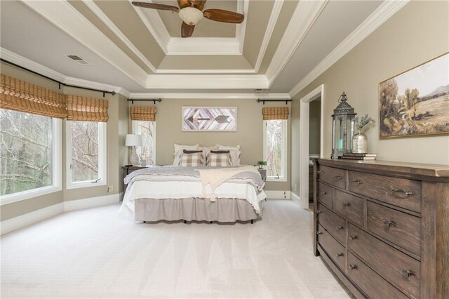 carpeted bedroom featuring a tray ceiling, multiple windows, baseboards, and ornamental molding