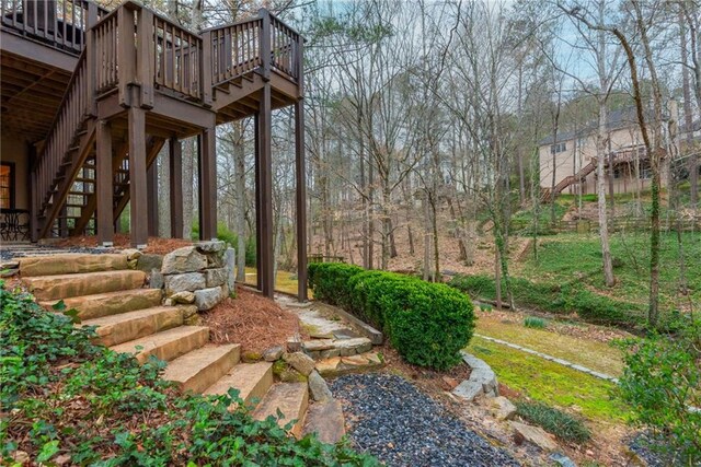 back of house with stucco siding, a lawn, stairway, and a deck