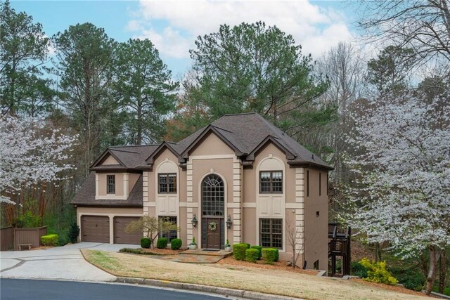 view of front facade featuring stucco siding, a front yard, concrete driveway, and a garage