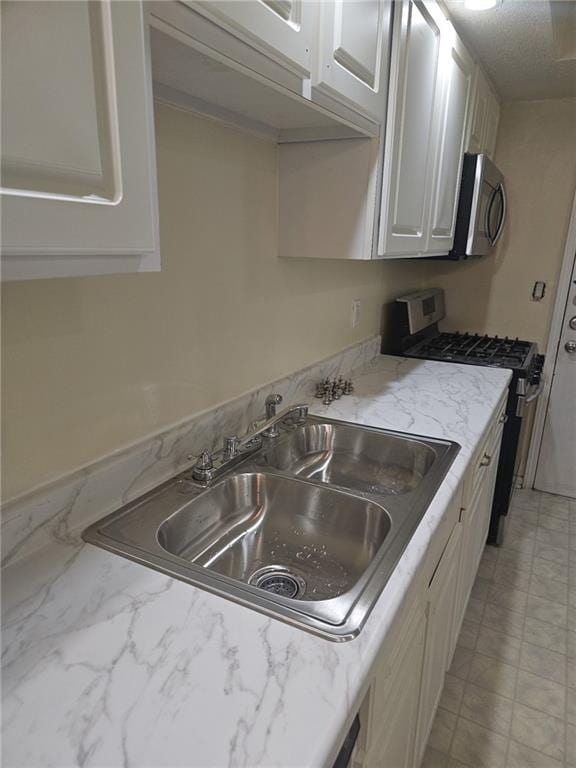 6851 Roswell Rd Unit 15, Atlanta, GA 30328 - kitchen featuring stainless steel appliances, white cabinets, and light stone countertops