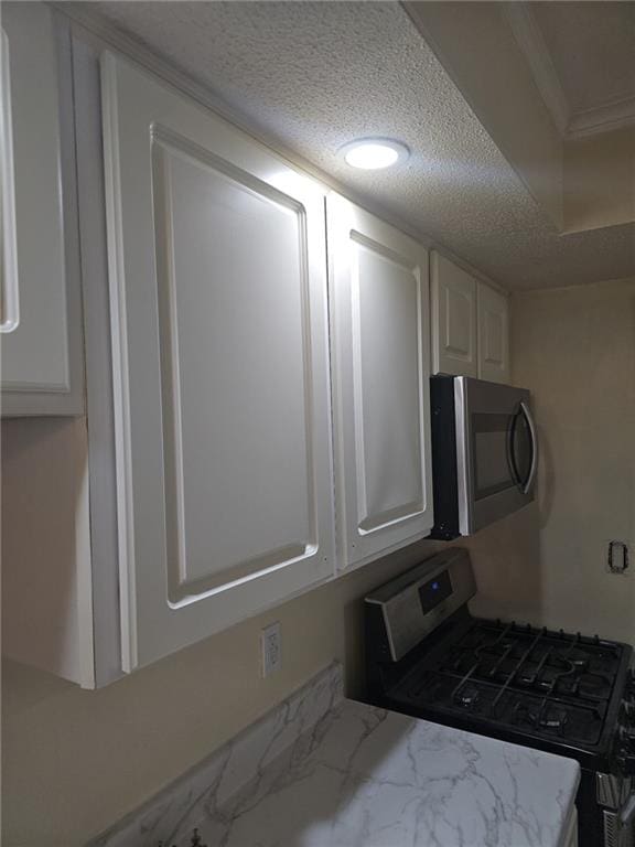 6851 Roswell Rd Unit 15, Atlanta, GA 30328 - kitchen featuring stainless steel appliances, white cabinetry, a textured ceiling, marble look tile flooring, and light stone countertops