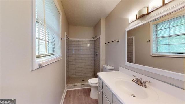 full bath with a wealth of natural light, tiled shower, toilet, and wood finished floors