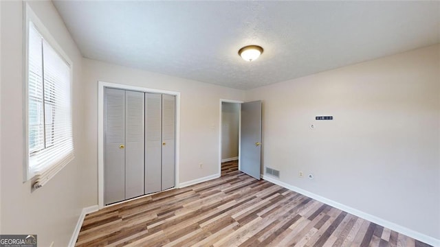 unfurnished bedroom with a closet, visible vents, baseboards, and light wood finished floors