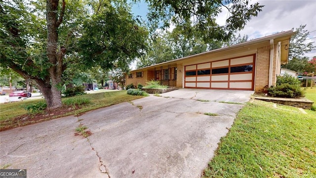 ranch-style house with an attached garage, driveway, a front yard, and brick siding