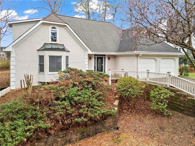 view of front of home with stucco siding, a shingled roof, and a garage