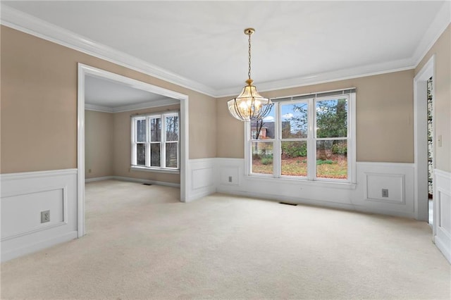 unfurnished dining area with visible vents, an inviting chandelier, ornamental molding, wainscoting, and carpet flooring