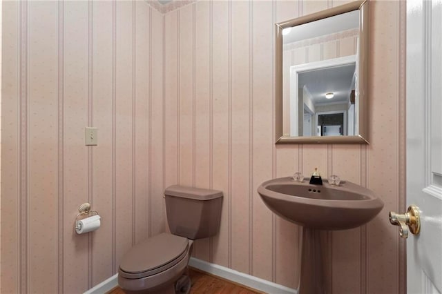 bathroom with toilet, wood finished floors, and baseboards