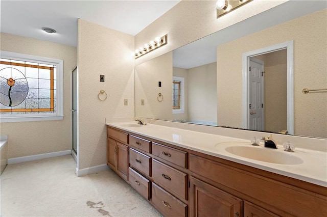 bathroom with double vanity, an enclosed shower, baseboards, and a sink