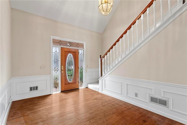 foyer entrance with stairway, wood finished floors, and visible vents