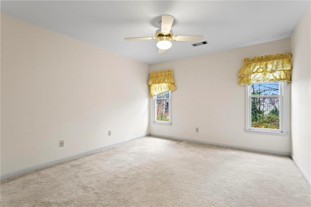 carpeted empty room with a ceiling fan, visible vents, and baseboards