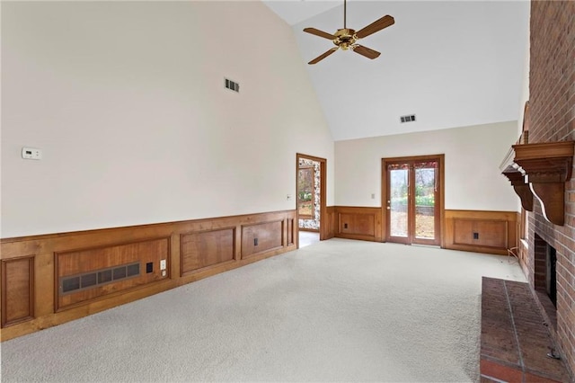 unfurnished living room featuring visible vents, a fireplace, carpet floors, and a wainscoted wall