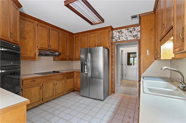 kitchen featuring visible vents, under cabinet range hood, light countertops, black appliances, and a sink