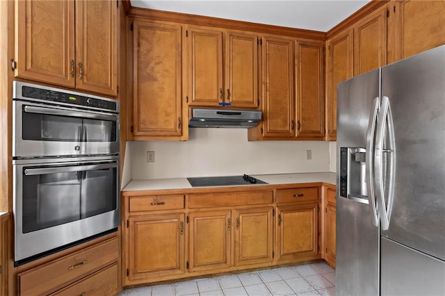 kitchen with under cabinet range hood, stainless steel appliances, brown cabinetry, and light countertops