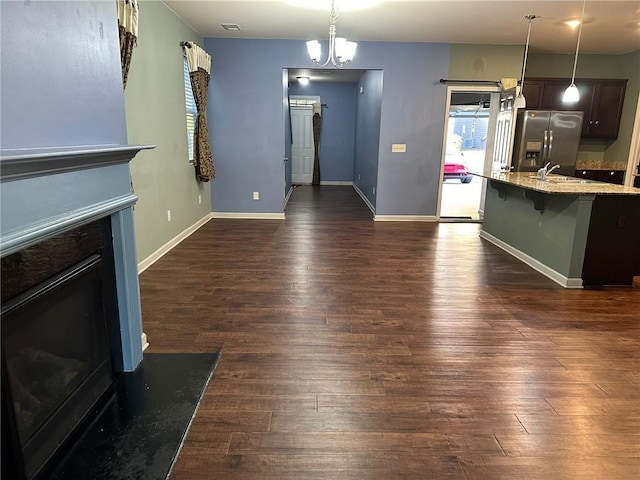 unfurnished living room featuring sink, an inviting chandelier, and dark hardwood / wood-style flooring