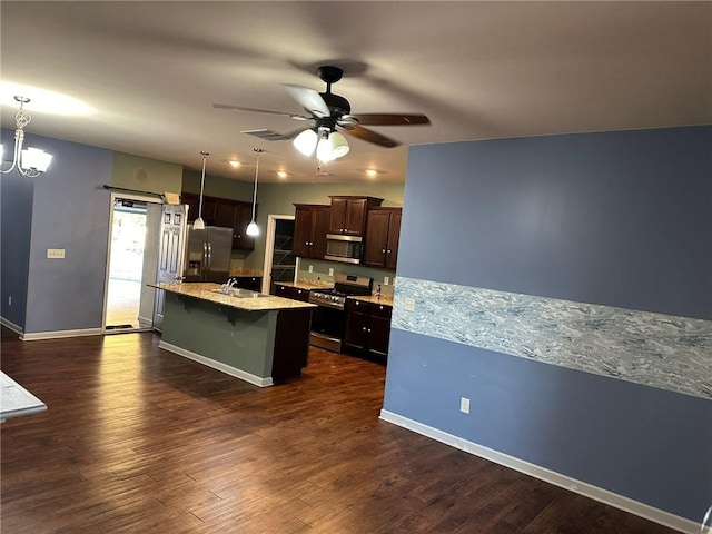 kitchen featuring a center island with sink, appliances with stainless steel finishes, light stone countertops, dark hardwood / wood-style floors, and pendant lighting