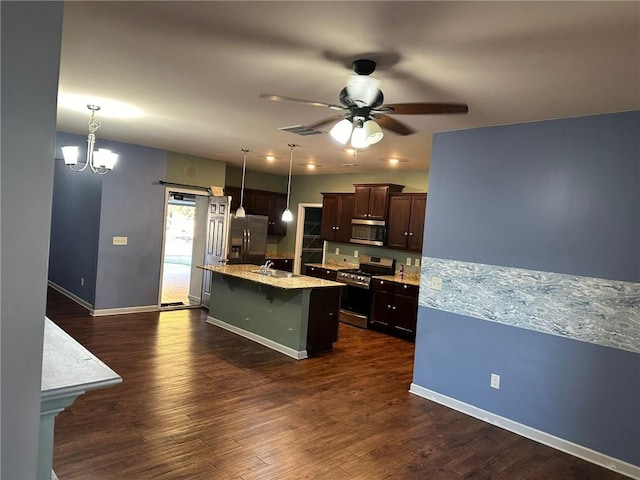 kitchen featuring an island with sink, dark hardwood / wood-style floors, pendant lighting, dark brown cabinetry, and stainless steel appliances