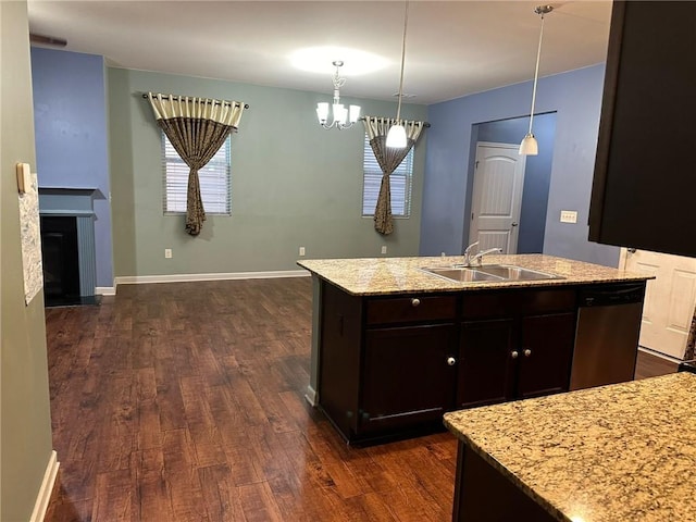 kitchen featuring a center island with sink, hanging light fixtures, dark hardwood / wood-style flooring, stainless steel dishwasher, and sink